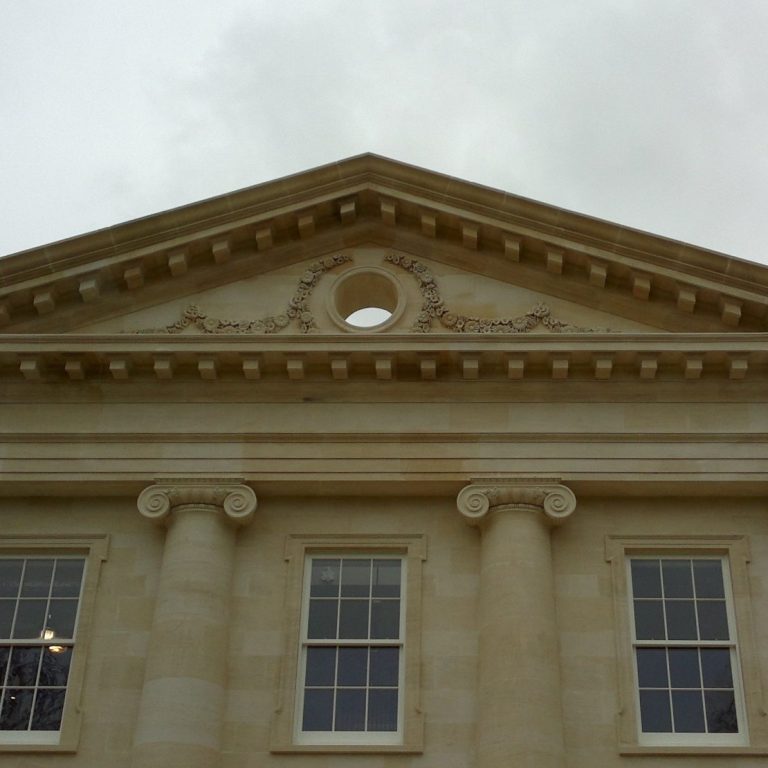 Ionic capitals and carved daisies around pierced tympanum